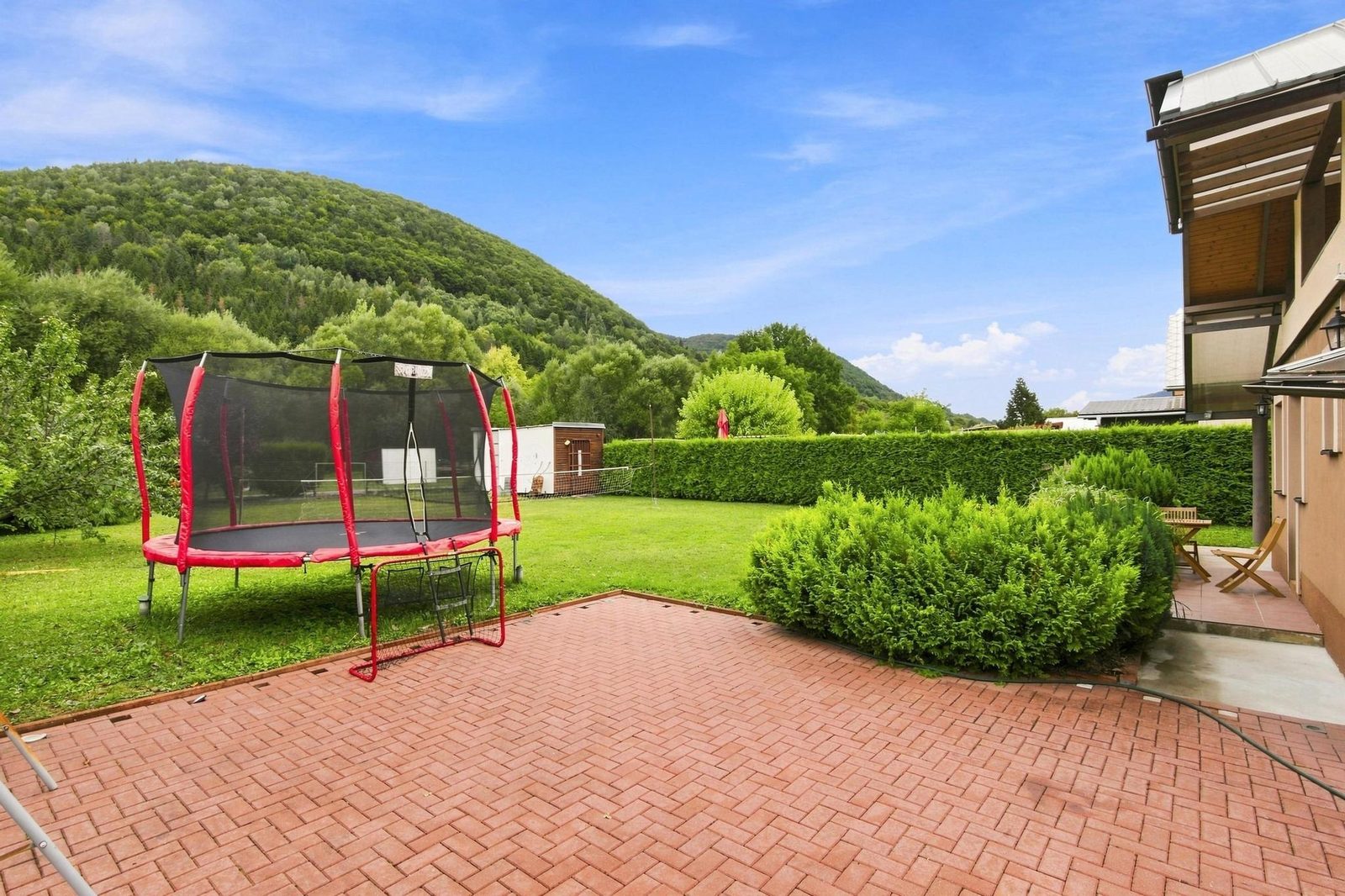 Trampolína a dláždená plocha v záhrade